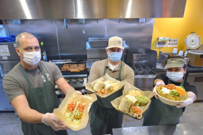 Burrito Bistro owner Chris Tucker, center, holds plates of the B2 Burrito and Burrito Max, while general manager Joao Motta, left, holds a plate of fish tacos and Noina Maneemas holds a tostada salad with chicken and black beans.