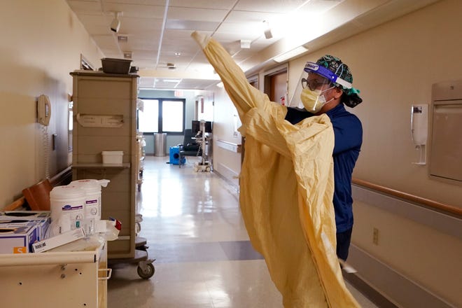 Registered Nurse Monica Quintana dons protective gear before entering a room at the William Beaumont hospital, April 21, 2021 in Royal Oak, Mich. Hospitals across Michigan are dealing with a surge in COVID-19 patients, including Bronson Battle Creek Hospital and Oaklawn Hospital in Marshall.