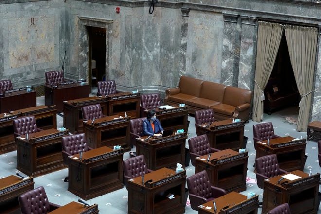 FILE - In this Jan. 13, 2021, file photo, Washington Sen. Emily Randall, D-Bremerton, works at her desk on the otherwise empty Senate floor, at the Capitol in Olympia during a joint session of the Washington Legislature being held remotely.