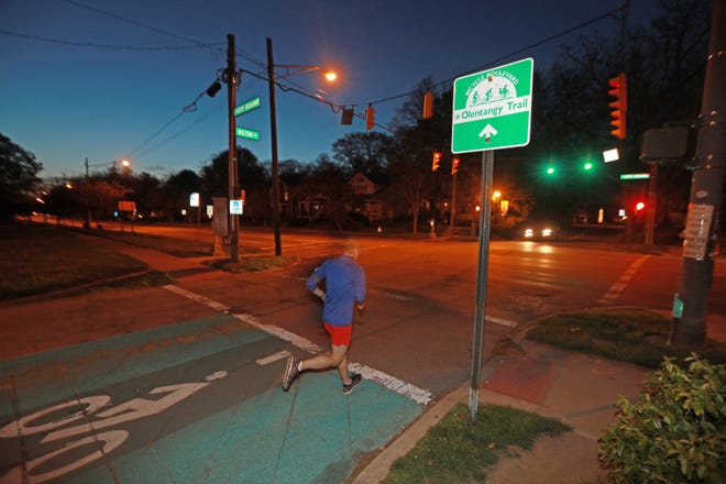 A runner on Milton Avenue crosses W. North Broadway Monday night. Columbus parks officials have selected a route to connect the Olentangy Trail through Clintonville.