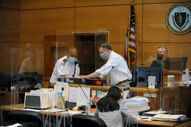 Masked and behind plexiglass partitions, Framingham District Court First Justice David Cunis and Assistant Clerk Magistrate George Marinofsky conduct arraignments,  many of them via zoom, April 28, 2021.  At left is Assistant Chief VCourt Officer Bobby Jackson. 