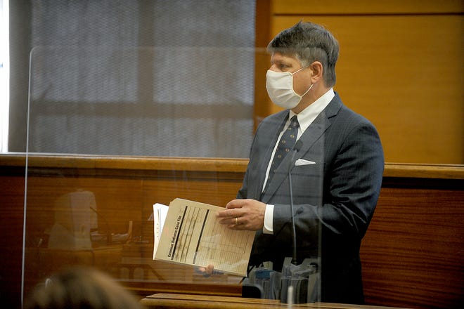 Masked and behind plexiglass partitions, defense attorney Mark Helwig represents a client at Framingham District Court, April 28, 2021.