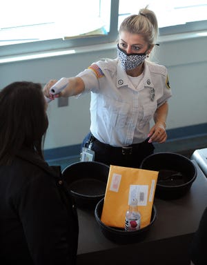 Framingham District Court Associate Court Officer Xhensila Isufi checks the temperature of a person entering the courthouse, April 28, 2021.