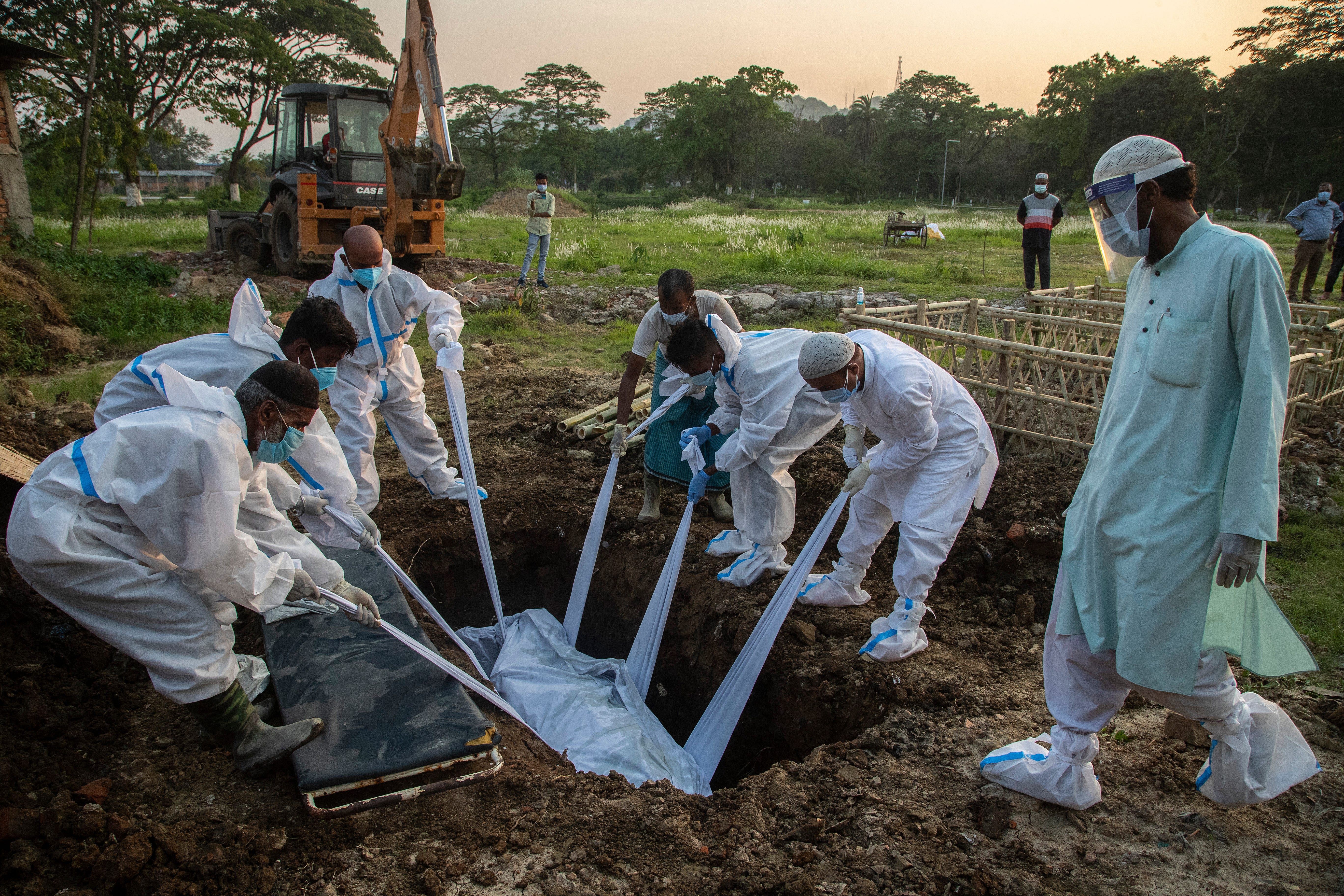Relatives and municipal workers in protective gear bury the body of a person who died due to COVID-19 in Gauhati, India, Sunday, April 25, 2021.