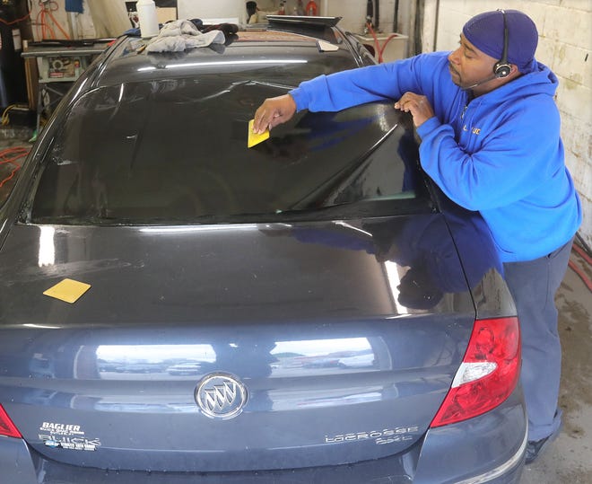 Joseph Easton Sr., owner of LJ Audio Enhancement, installs window tinting on a customer's car.