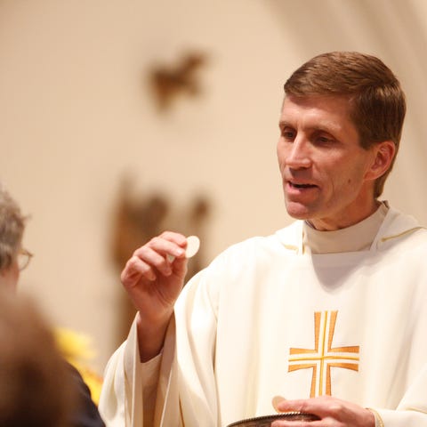 Monsignor William Koenig gives Communion during a 