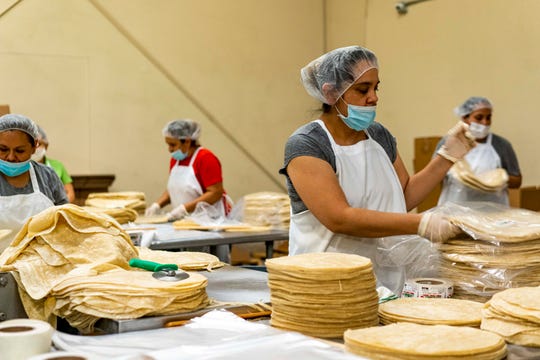 A woman packs tortilla with other employees at La Sonorense Tortilla Factory in Phoenix, Ariz.