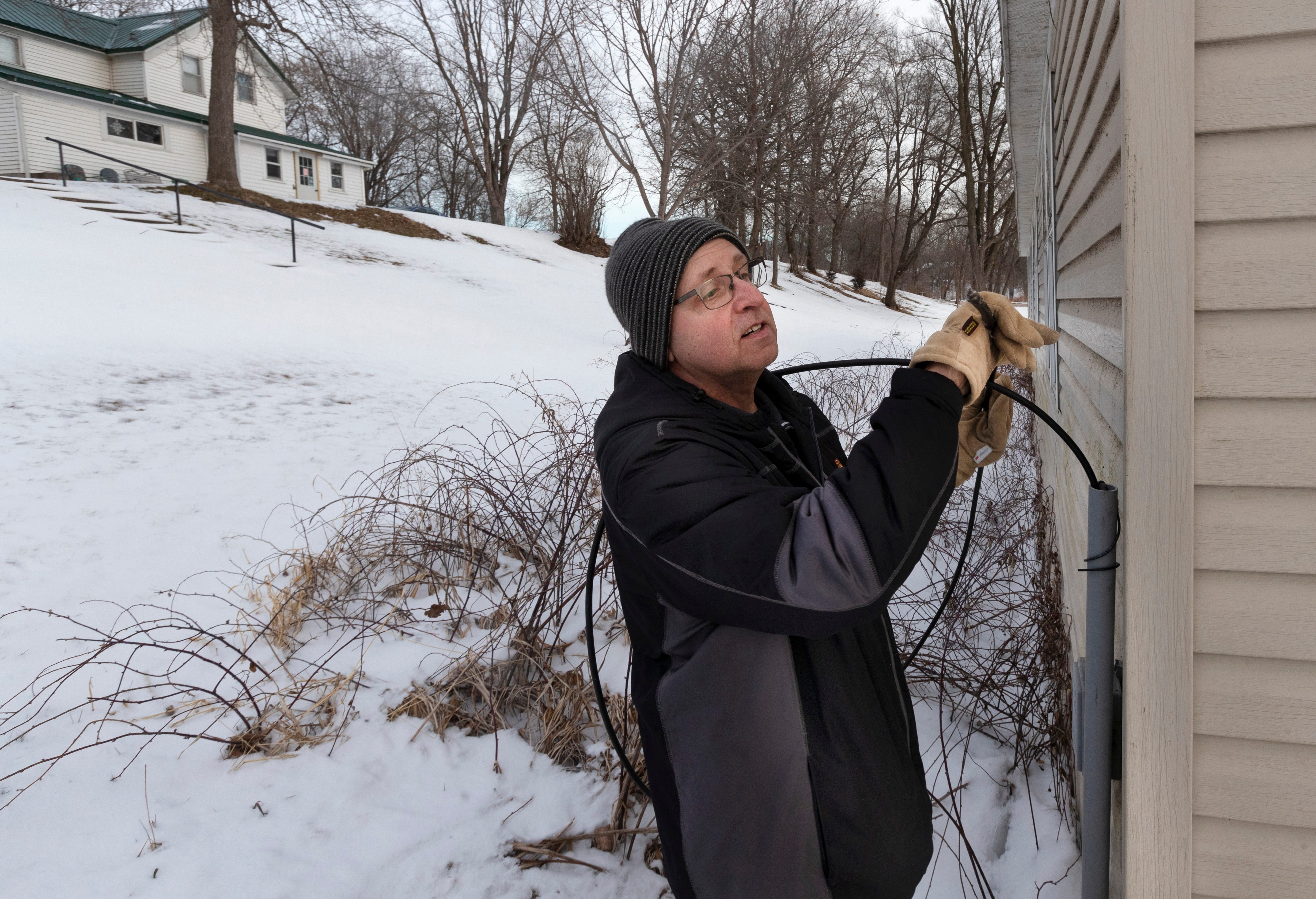 Todd Mehrkens holds the fiber-optic cable that was trenched to his house in 2020 in Hager City.