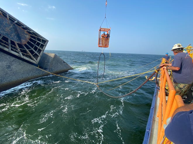 Contracted salvage divers transport a hose to the Seacor Power fuel tank May 3 to start removing the fuel from the capsized oilfield boat, about 8 miles south of Port Fourchon. The Coast Guard said all of the fuel was removed within about two weeks. Salvage operations are continuing.