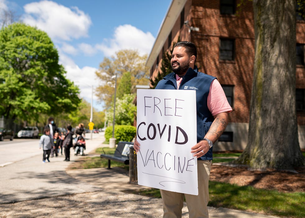 Luis Mateo, from the United Way, holds a sign for free vaccines on May 6, 2021, in Worcester, Mass.