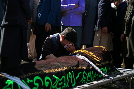A man cries over the body of a victim of deadly bombings on Saturday near a school, at a cemetery west of Kabul, Afghanistan, on May 9, 2021. The Interior Ministry said Sunday the death toll in the horrific bombing at the entrance to a girls' school in the Afghan capital has soared to some 50 people, many of them pupils between 11 and 15 years old, and the number of wounded in Saturday's attack has also climbed to more than 100.