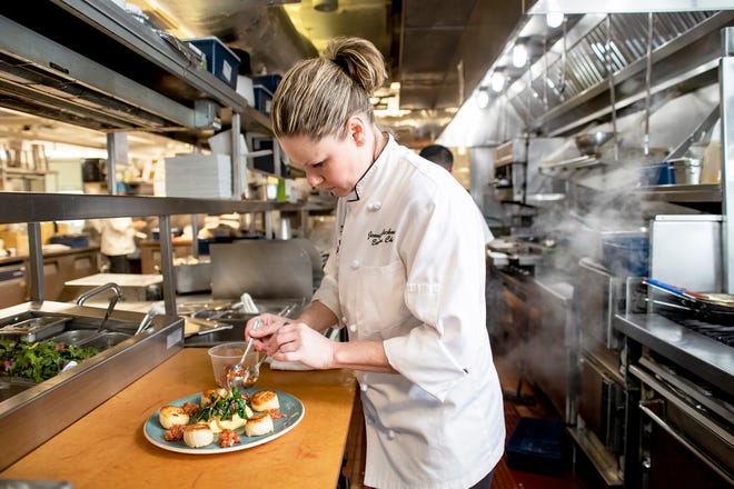 Jennifer Backman, executive chef at the Mooring Seafood Kitchen & Bar, plates an order of pan-seared scallops.
