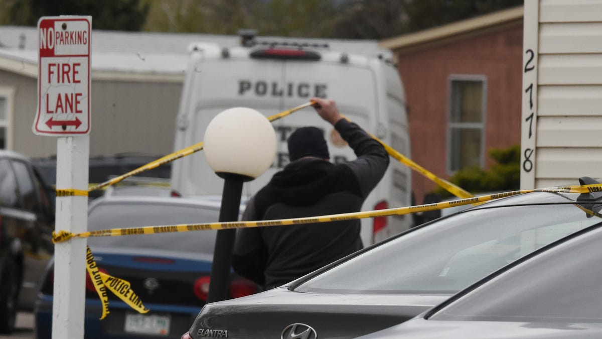 A Colorado Springs Police Department officer lifts up crime tape at the scene where multiple people were shot and killed early Sunday, May 9, 2021, in Colorado Springs, Colo.