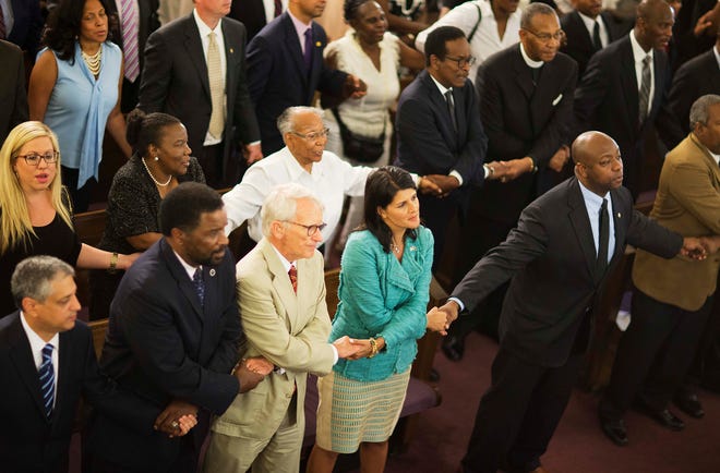 South Carolina Gov. Nikki Haley joins hands with Charleston Mayor Joseph Riley and Sen. Tim Scott, R-S.C., at a memorial service at Morris Brown AME Church for the people killed during a prayer meeting inside the historic black church in Charleston, S.C.