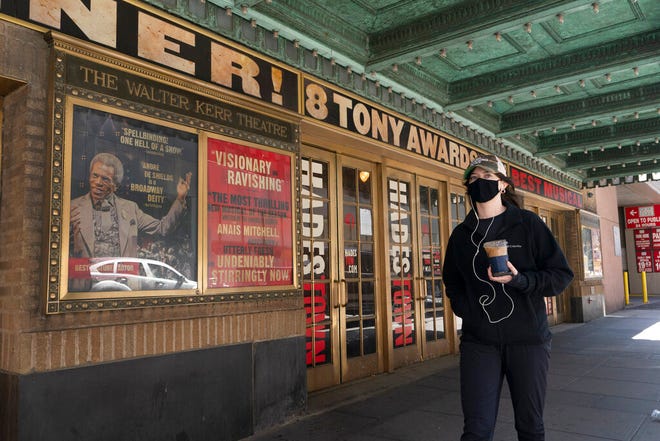 A woman walks past the Walter Kerr Theatre, Thursday, May 6, 2021, in New York where Hadestown was showing before the coronavirus pandemic forced its closing a year ago. Gov. Andrew Cuomo has announced that Broadway theaters can reopen Sept. 14, 2021. (AP Photo/Mark Lennihan)