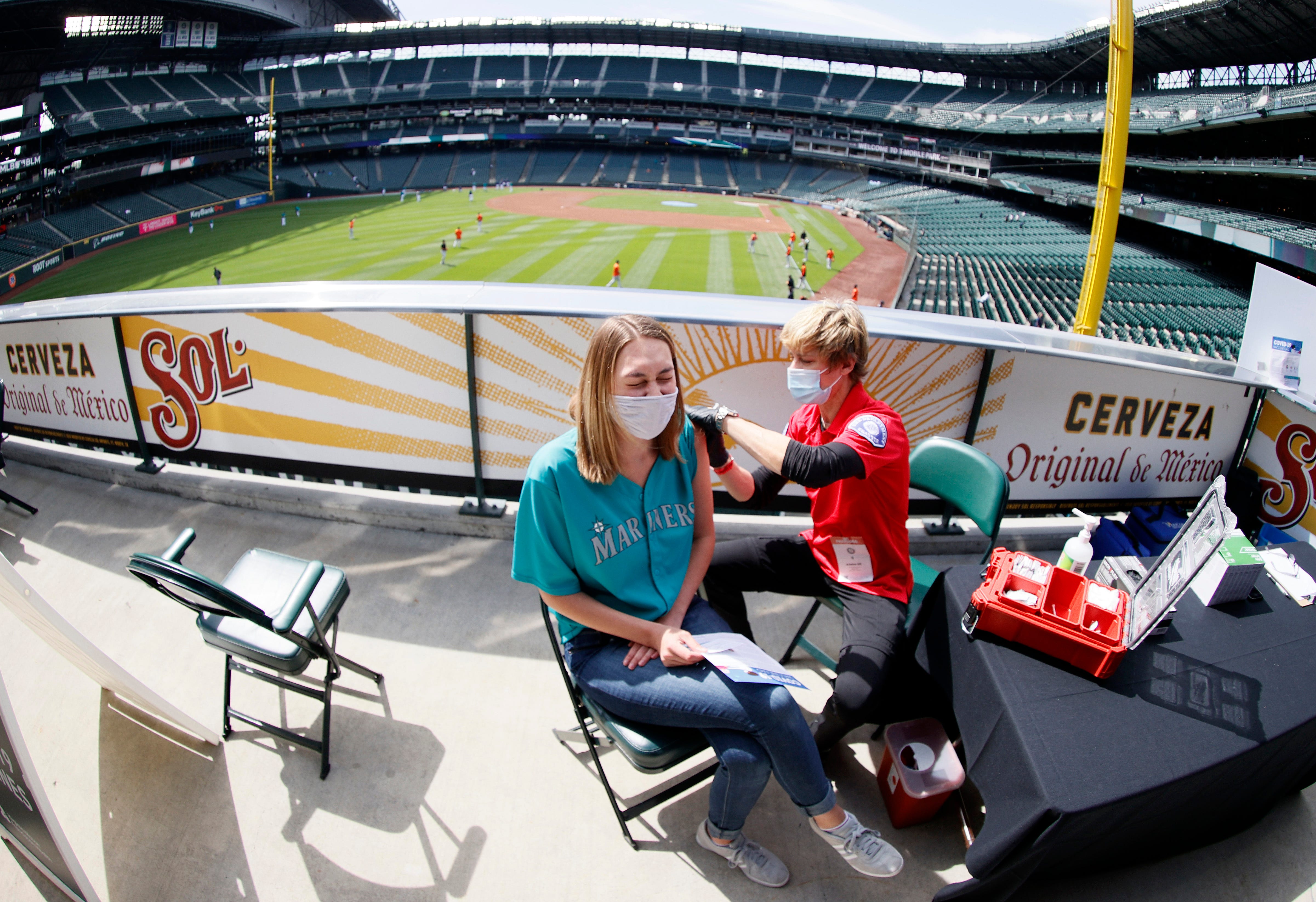 Aeryal Thomsen, left, receives her COVID-19 vaccination before a game between the Seattle Mariners and the Baltimore Orioles on May 5 at T-Mobile Park in Seattle.