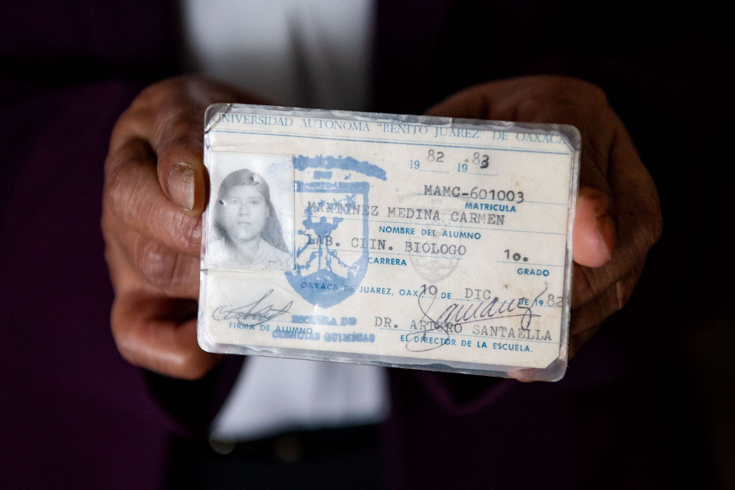 Carmen Medina Martinez holds up her student identification card from when she was enrolled at the Benito Juárez Autonomous University of Oaxaca, a public university located in Oaxaca, Mexico. Medina Martinez studied biology, then became a nurse before coming to the United States. But in America, where she did not speak English, she could only find manual labor work.