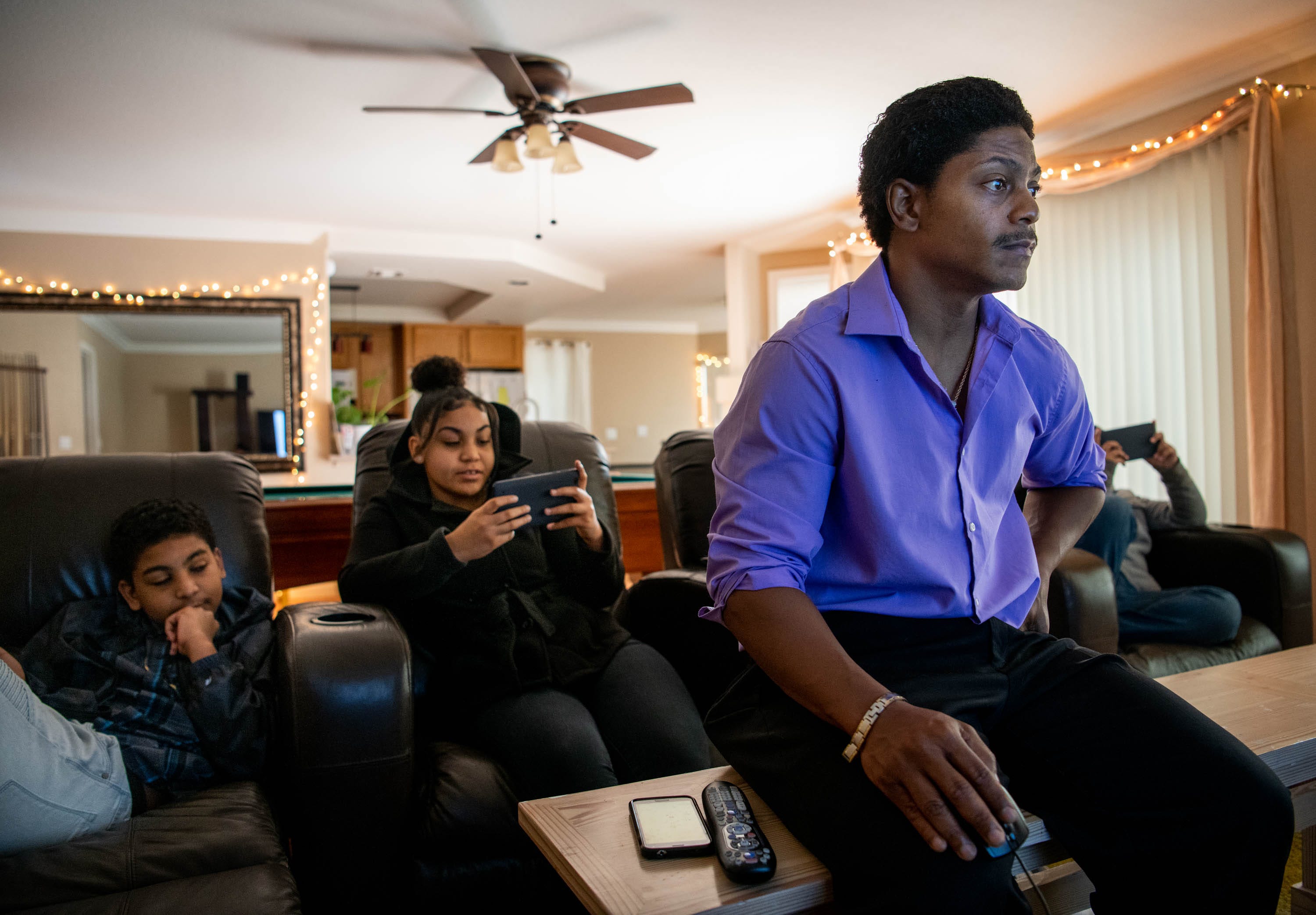 Kendrick Harrison pores over dozens of email exchanges with Argosy University, a for-profit college that closed without warning. Kendrick's children, Alex, left, 14, and Sierra, 18, are seated behind him.