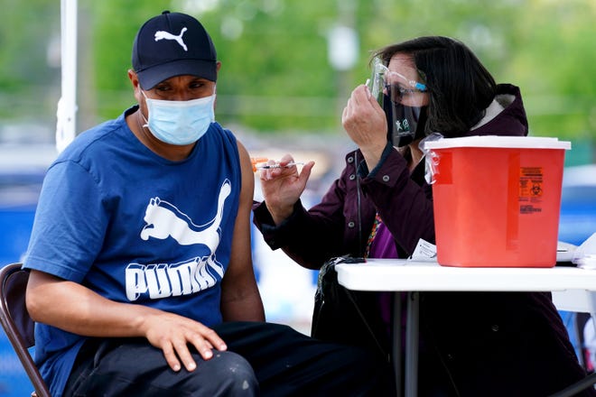 Hamilton County Public Health nurse Patty Laube administers a vaccination against COVID-19 to Lionel Franco, Monday, May 10, 2021, at Yorktowne Mobile Home Park in Sharonville, Ohio.