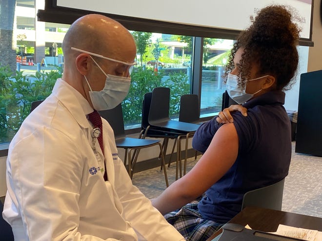 Olivia Graham, 14, lifts her sleeve to get her first dose of the Pfizer COVID-19 vaccine at OhioHealth's David P. Blom Administrative Campus on Thursday. Graham and her brother, 12-year-old Solomon, said they're looking forward to traveling and sleepovers again after the pandemic. Dr. Joe Gastaldo, OhioHealth's medical director for infectious disease, administered some of the first shots to kids on Thursday.
