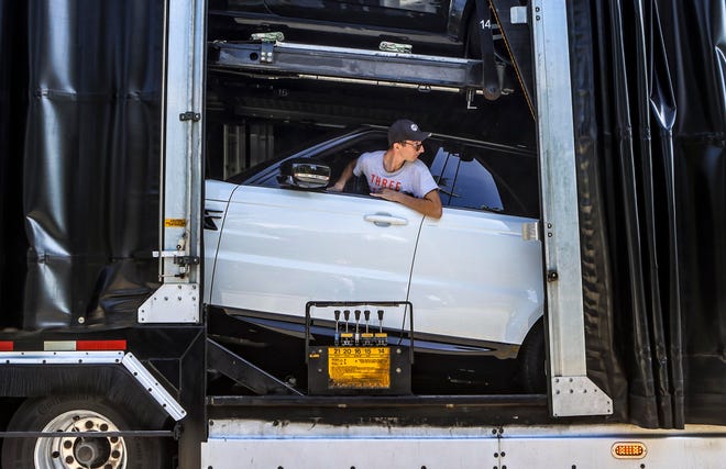 Daniel Mereuta of the Royal Team auto transport company carefully backs an SUV onto a trailer along Brazilian Avenue in May.