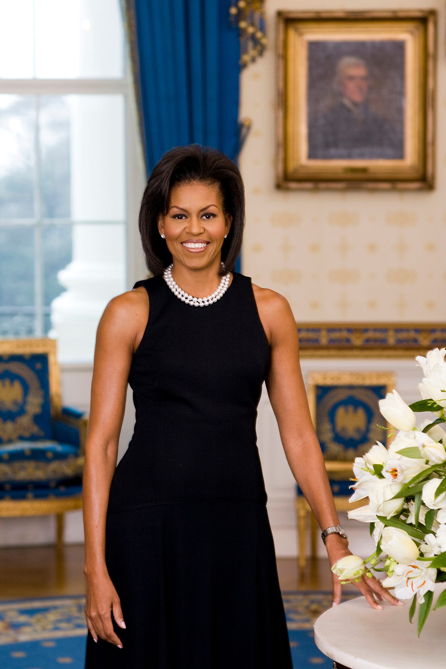 In this handout image provided by the White House, first lady Michelle Obama poses for her official portrait in the Blue Room of the White House in February 2009 in Washington.