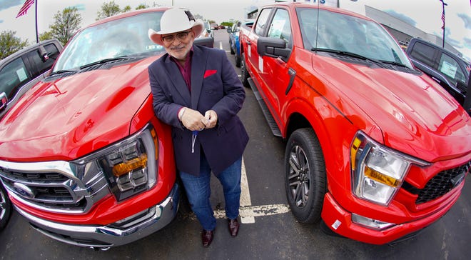 In this photo made on Thursday, May 6, 2021, Shults Ford dealership owner Richard Bazzy stands between two of the remaining Ford F150 pickups on the front line on their dealership lot in Wexford, Pa.