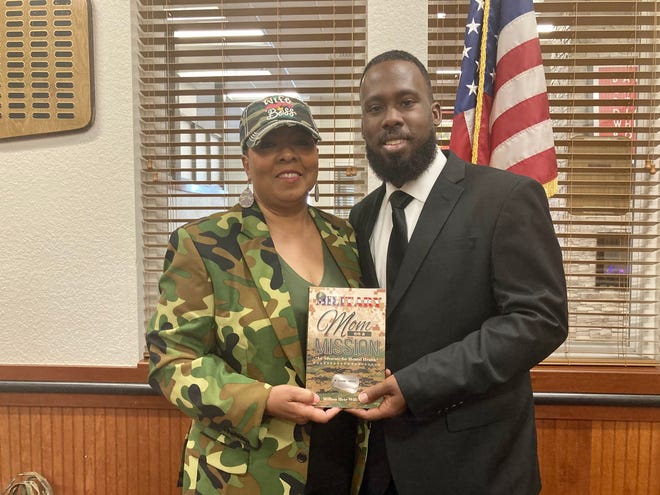Million Heir-Williams, left, and her son Jerome Brown, a U.S. Marine Corps veteran, pose for a photo with a copy of her book Military Mom on a Mission: An Advocate for Mental Health at an event in Jacksonville, May 14, 2021.