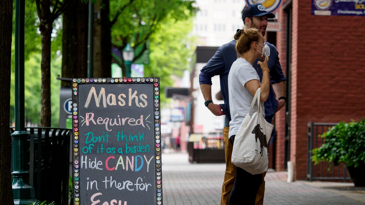 Ryan Furey stands with Monique Howard as she puts on her mask as she contemplates entering Rocket Fizz in Chattanooga, Tenn.