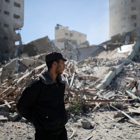 Palestinian policeman stands at rubble of a buildi