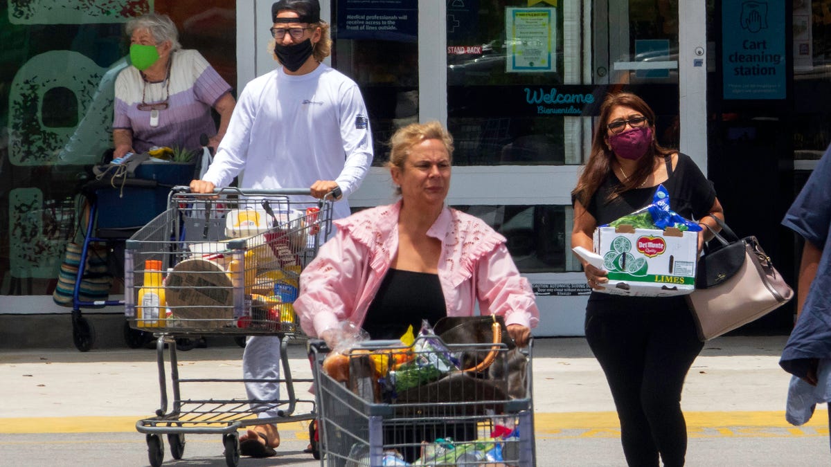 Masked and unmasked customers leave the ALDI store on Okeechobee Boulevard in West Palm Beach Monday, May 17, 2021. The store still has a sign on the door requiring masks. 