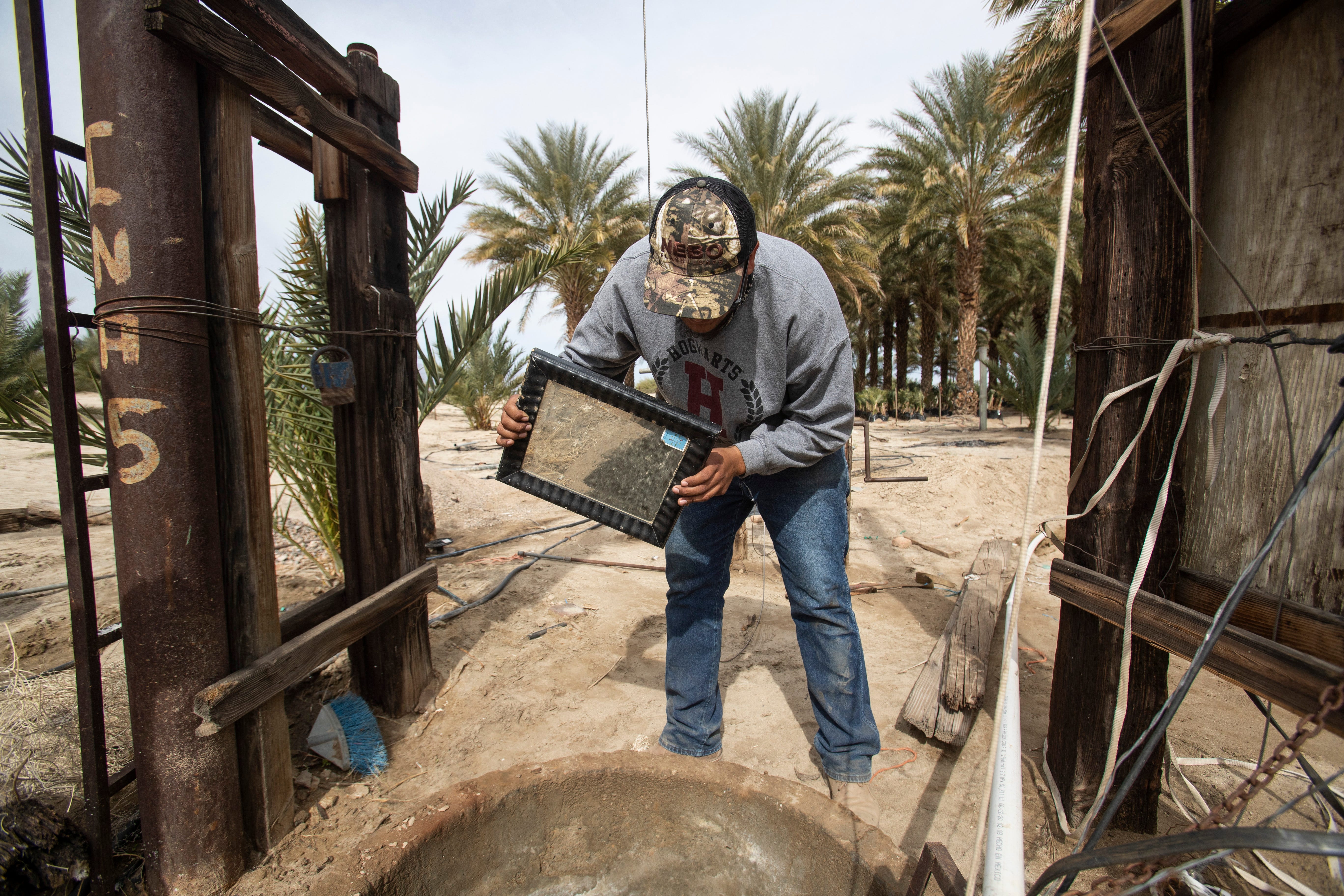 Eliseo Vieyra uses a mirror to shine light inside a well on his family's date farm in Ejido Federico Martinez Manatou. He says the farm would not see disturbance if a project to deliver water to the Salton Sea from the Sea of Cortez would be developed nearby.