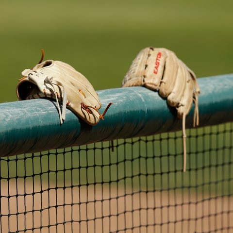 Gloves sit on the dugout wall during a game