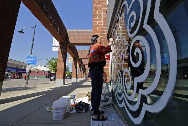 Artist Nou Vue of Appleton paints paj ntaub, a Hmong textile art that reflects forms in nature, on the outside of the Fox Cities Performing Arts Center in Appleton. The mural celebrates Hmong storytelling and culture as part of Hmong Heritage Month.