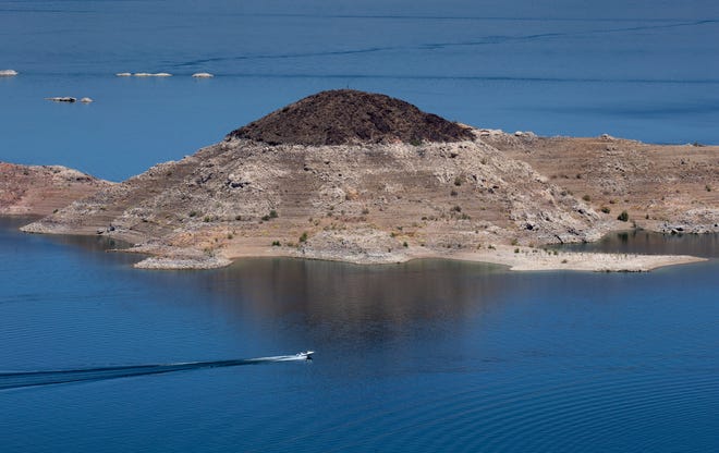 A boat cruses past Rock Island on May 12, 2021, in the Lake Mead National Recreation Area, on the Arizona/Nevada border. A high-water mark or bathtub ring is visible on the shoreline.