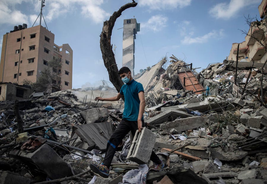 A Palestinian man inspects the damage of a six-story building which was destroyed by an early morning Israeli airstrike, in Gaza City, on May 18, 2021. Israel carried out a wave of airstrikes on what it said were militant targets in Gaza, leveling a six-story building in downtown Gaza City, and Palestinian militants fired dozens of rockets into Israel early Tuesday, the latest in the fourth war between the two sides, now in its second week.
