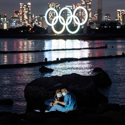 A couple poses for pictures before the lit Olympic
