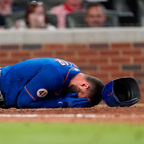 The New York Mets' Kevin Pillar lies on the ground