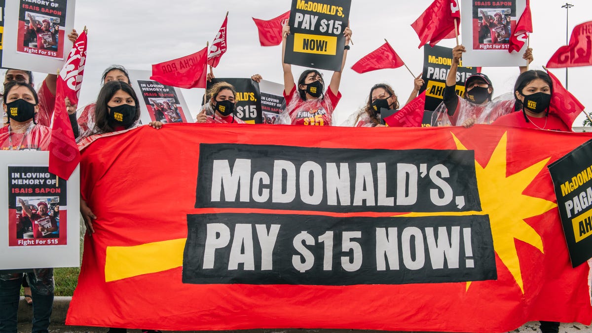 Women chant and display banners during a rally on May 19, 2021 in Houston, Texas. Fast-food workers, community members, and activists gathered nationwide to demand McDonald's to raise its minimum wage to $15 an hour. 