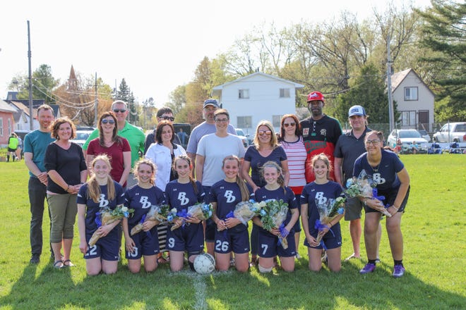 Sault High girls soccer seniors and their parents are pictured on Senior Night. The Blue Devils' seniors were honored at hafltime, and they include, front row, from left:  Lauryn Wood, Sophie Swedene, Abby Sarley, Aliah Robertson, Madison LaBonte, Alexus Adair and team manager Kowana Higgins. The Blue Devils tied Oscoda 0-0 on Monday.