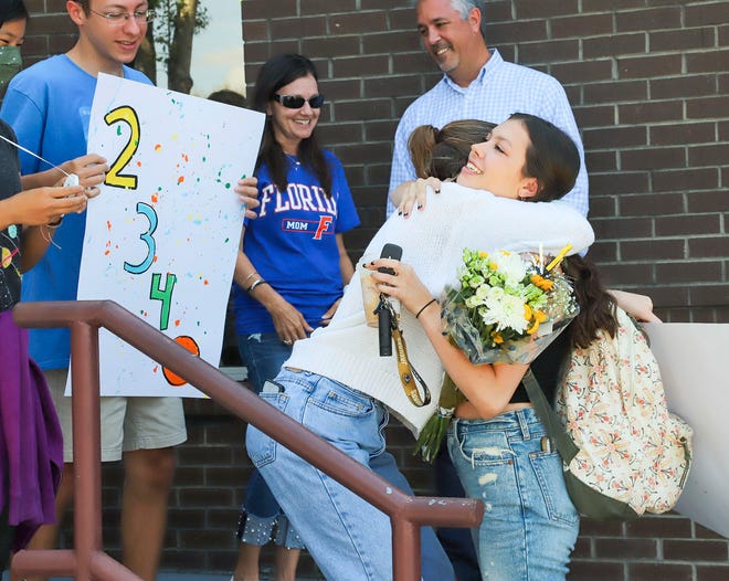 Niceville High School Senior Laurel Wentworth is hugged by Emma Wagner on Friday as Laurel was greeted with a surprise celebration as she arrived for her final day of school. Lauren had a perfect attendance record in her 2,340-day school career.