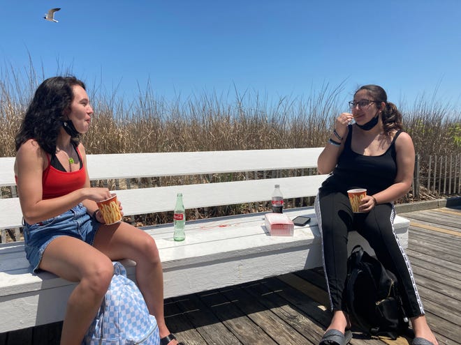 High school seniors Cocoa Houck and Maliyah Saldona enjoy some boardwalk french fries Friday, May 21, 2021. They said they noticed less enforcement of mask-wearing on the boardwalk.