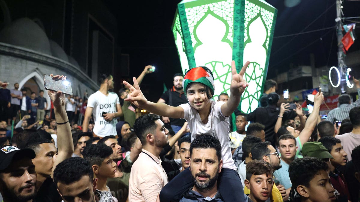 People celebrate in the streets following a ceasefire brokered by Egypt between Israel and the ruling Islamist movement Hamas, in Rafah, in the southern Gaza Strip on May 21, 2021.