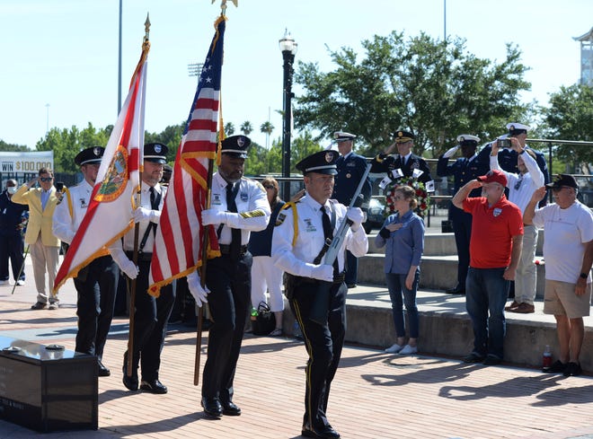 The honor guard of the Jacksonville Sheriff's Office presents the colors Saturday during a wreath-laying ceremony at the Veterans Memorial Wall downtown ahead of next Memorial Day weekend. Families lay wreaths at the wall near their loved ones' names. The event was recorded for broadcast on Memorial Day and a virtual ceremony.