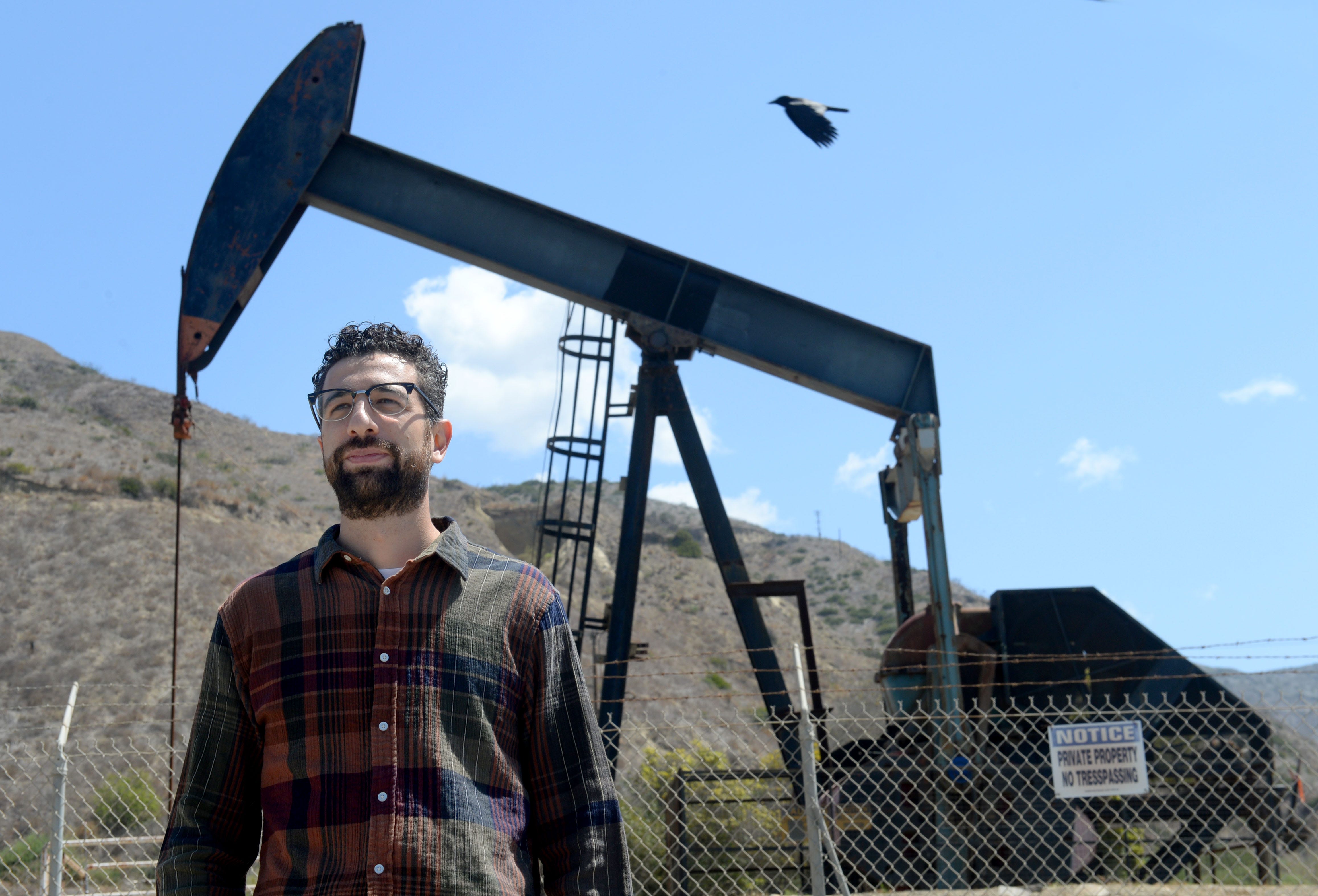 Tomas Rebecchi, an organizer with environmental group Food and Water Watch, stands near an oil well owned by California Resources Corporation along the Central Coast.