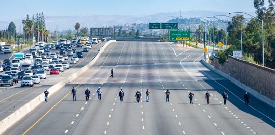 Police investigators walk along the closed northbound lanes of the 55 freeway south of Chapman Avenue looking for evidence following a shooting, Friday, May 21, 2021 in Orange, Calif. A 6-year-old boy seated in the backseat of his mother’s car on a Southern California freeway was shot to death by another motorist on Friday, authorities said.