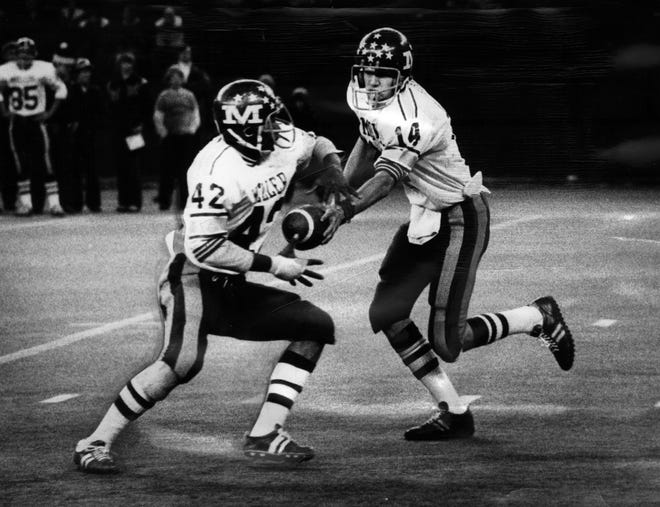 Moeller quarterback Tim Koegel hands off to running back Steve Givens in November 1976.