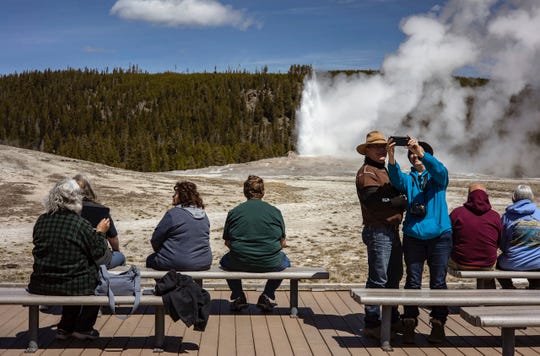Tourists watch Old Faithful erupt at Yellowstone National Park in April, a month that saw record visitation to the park.