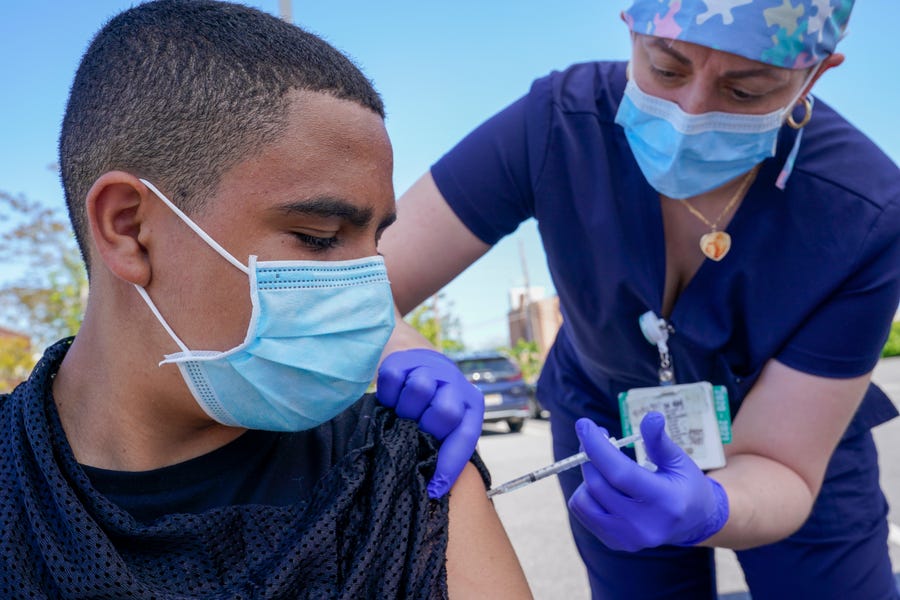 Justin Bishop, 13, watches as registered nurse Jennifer Reyes inoculates him with a Pfizer COVID-19 vaccine at the Mount Sinai South Nassau Vaxmobile site in Freeport, New York. US health officials say that most fully vaccinated Americans can skip testing for COVID-19, even if they were exposed to someone infected.