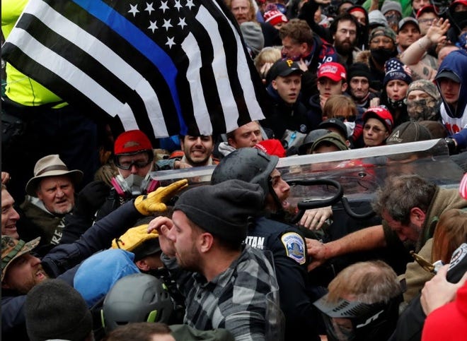 A thin blue line flag is held by a protester as Trump supporters fight with police during the Capitol riots on Jan. 6, 2021.